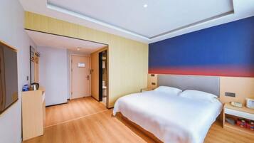 A hotel room with a large bed, a desk, and a wardrobe.