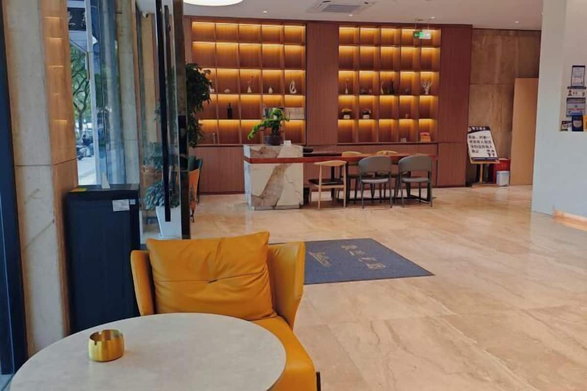 A lobby with a reception desk, seating area, and a wall with shelves.