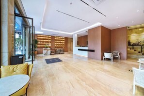 A hotel lobby with a reception desk, seating area, and a staircase. - Qiu shan Hotel (Wenzhou)