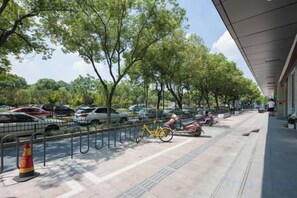 A parking area with cars, a yellow bicycle, and a pedestrian walkway. - Qiu shan Hotel (Wenzhou)