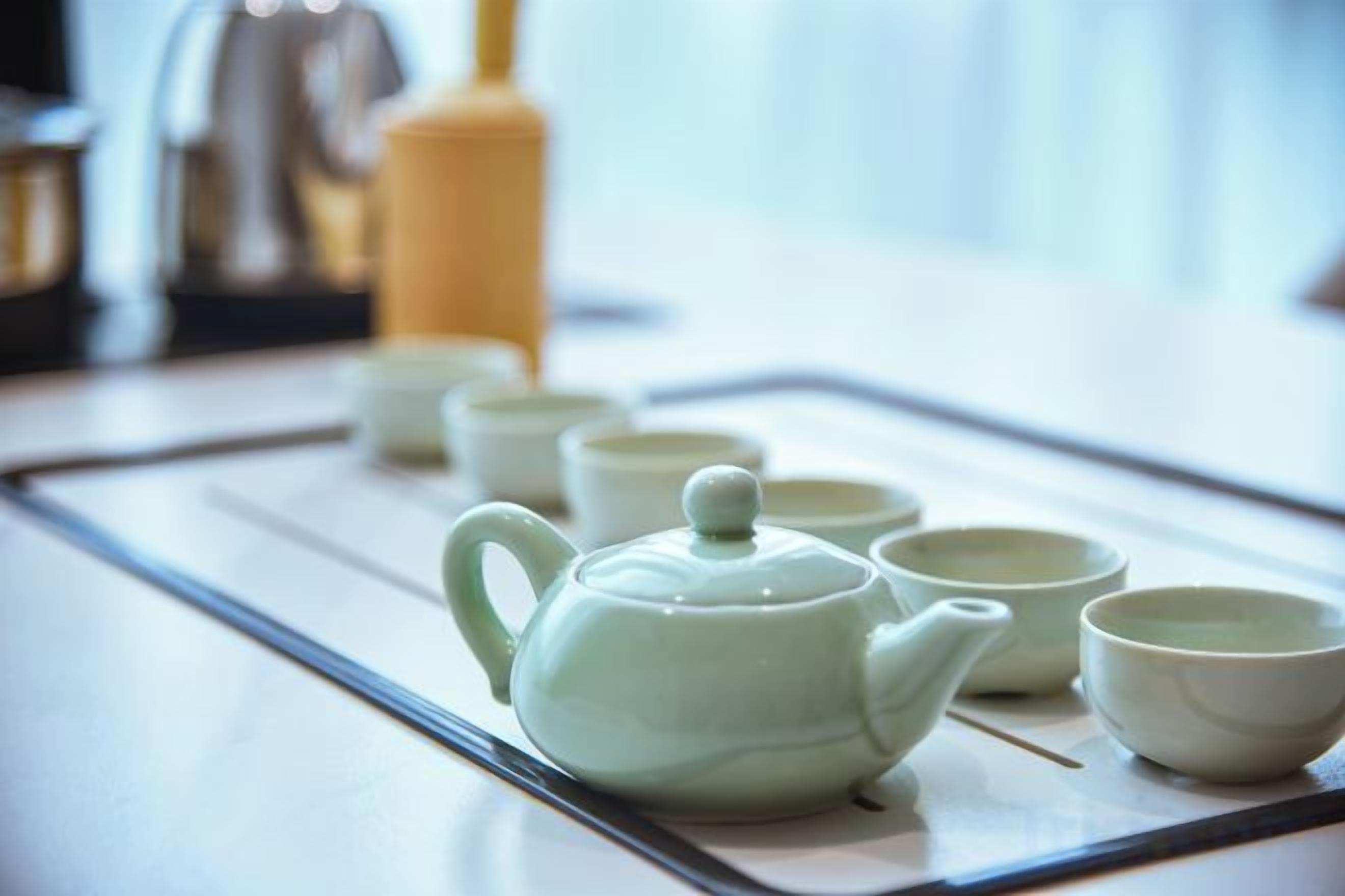 Un plateau avec une théière et plusieurs tasses, probablement pour servir le thé.