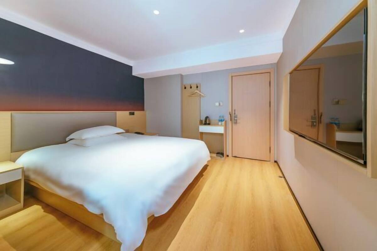 A modern bedroom with a bed, bedside table, and a large mirror.