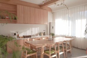 Een moderne keuken met houten kasten, een centraal eiland en een eethoek met een tafel en stoelen.