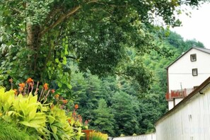 A building with a white exterior and a balcony, surrounded by lush greenery and trees. - Hangzhou Zhinan Zhibei Homestay (Hangzhou)