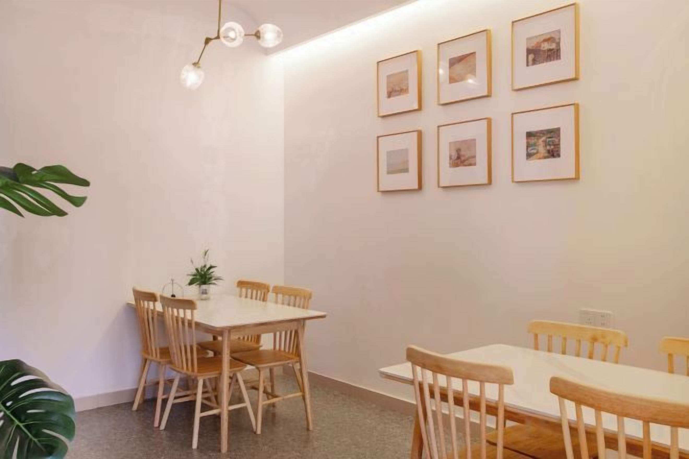 A dining area with a round table and chairs, framed pictures on the wall, and a plant.