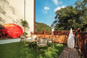 Un patio al aire libre con cerramiento de madera, una sombrilla blanca y una mesa con sillas.