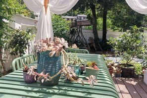 Un espace extérieur aménagé avec des sièges, des plantes en pot et un auvent blanc.