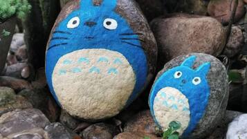 Two painted rocks with animal faces, surrounded by natural stones and greenery.