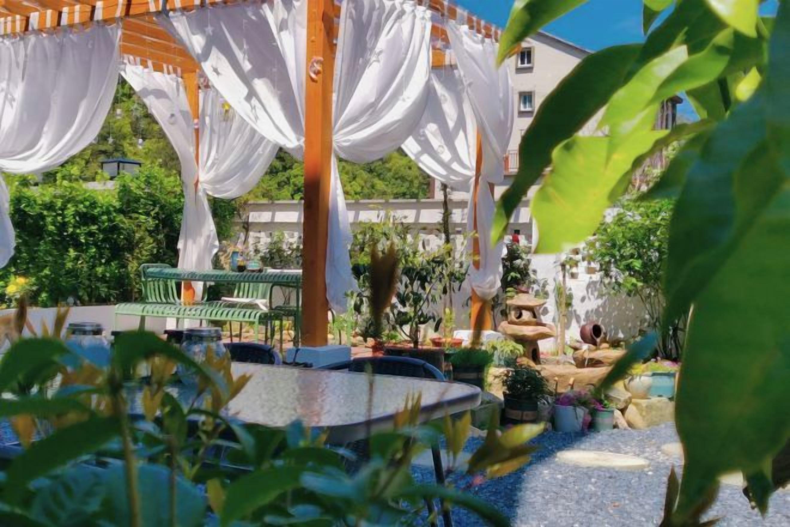 A gazebo with white drapes, a round table, and a bench.