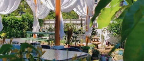 A gazebo with white drapes, a round table, and a bench.