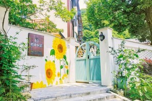 Una entrada protegida con un mural de girasoles, una escalera y un edificio con un letrero.