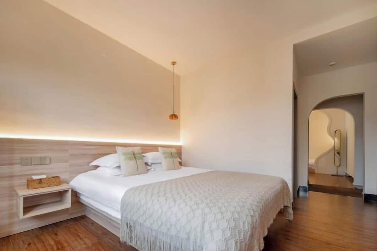 A modern bedroom with a bed, bedside table, and a unique wall-mounted light fixture.