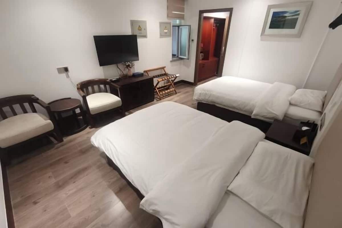 Una habitación de hotel con dos camas, televisión, escritorio y silla.