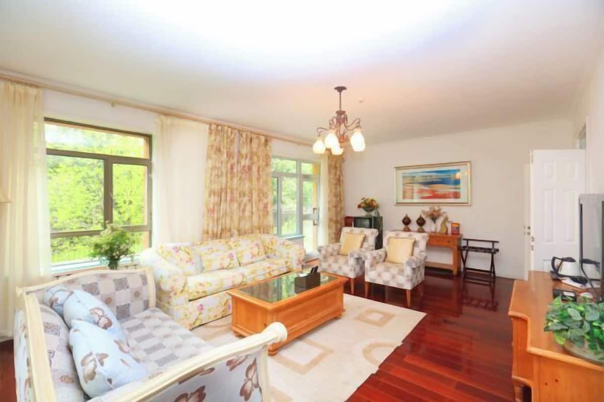 Una sala de estar con sofá, sillón, mesa de centro y televisor.
