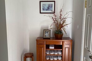 Un meuble en bois avec un tableau encadré et une plante en pot, un petit tabouret et une porte avec une poignée de porte.