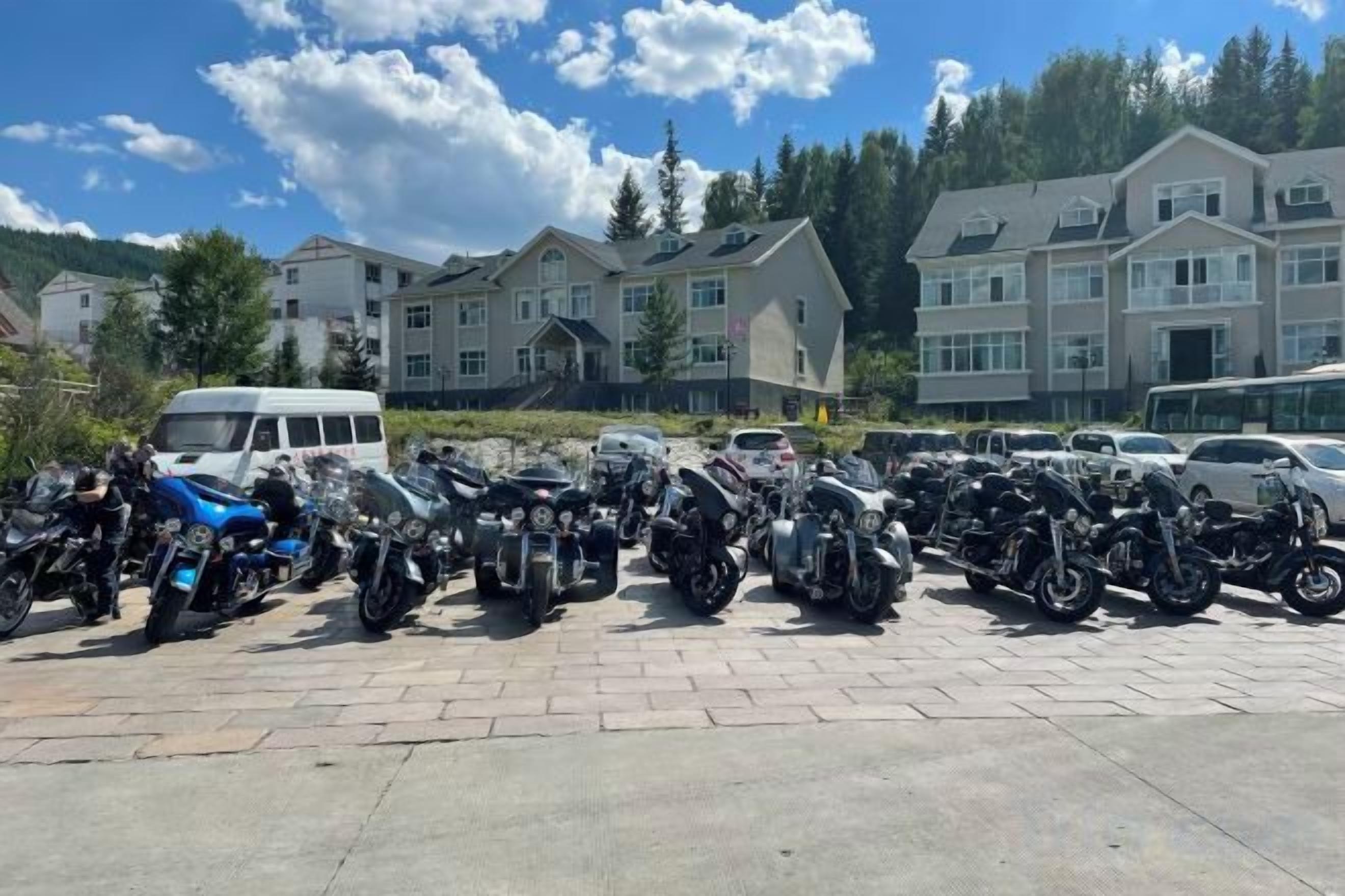 A parking lot with multiple motorcycles and a white van.
