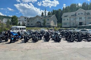 A parking lot with multiple motorcycles and a white van.