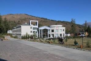 Un bâtiment moderne doté d’un atrium central, entouré d’une zone pavée et d’un paysage vallonné.
