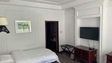 A hotel room with a bed, a TV, a desk, and a chair.