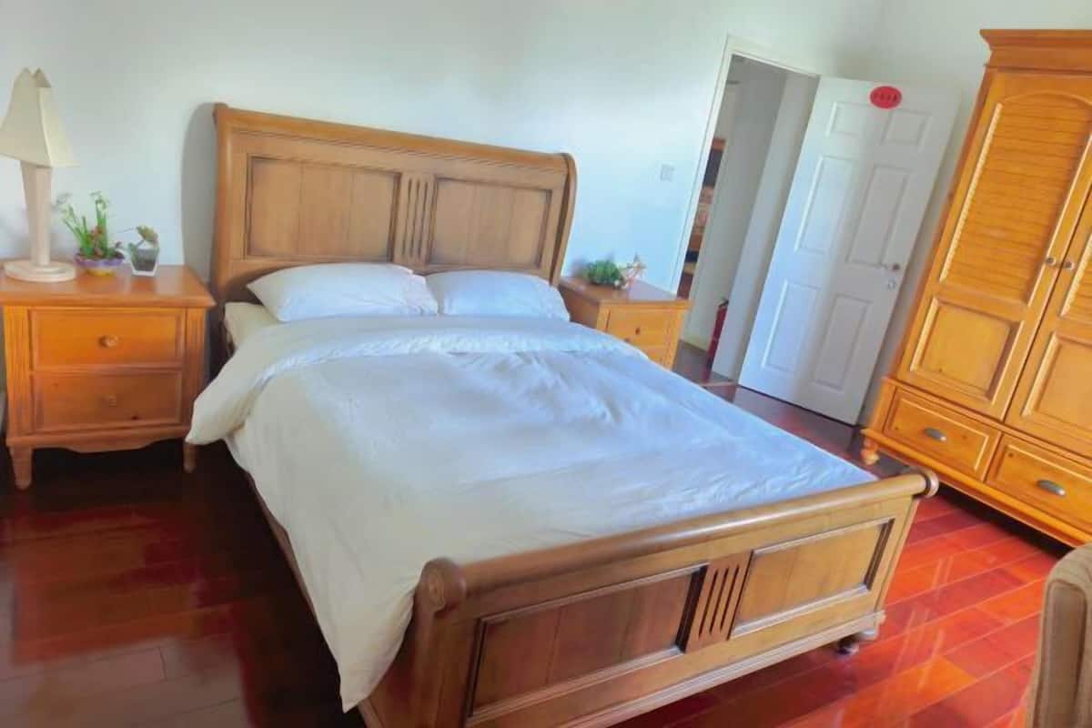 Un dormitorio con una cama de madera, mesitas de noche, un armario y una puerta.