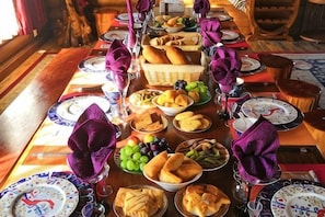 A dining table set with plates, glasses, and various food items.