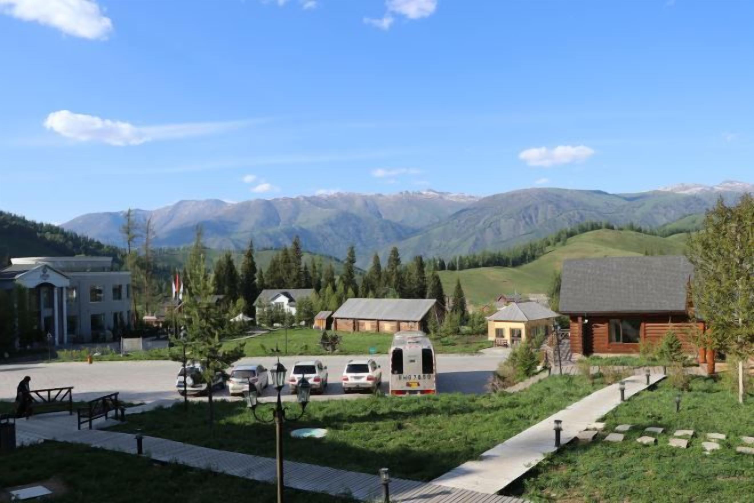 A residential area with houses, a paved walkway, and mountains in the background.