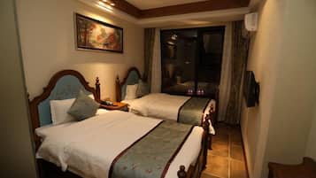 A hotel room with two beds, a painting on the wall, and a view through a glass door.