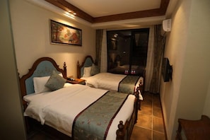 Habitación de hotel con dos camas, un cuadro en la pared y vista por una puerta de cristal.