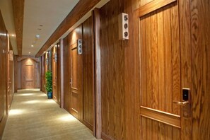 Un pasillo de hotel con puertas de madera numeradas 508 y 509, piso alfombrado y una planta en maceta.