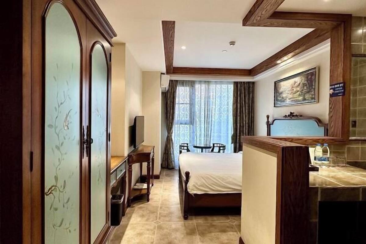 A hotel room with a bed, a desk, a chair, a wardrobe, and a bathroom area.