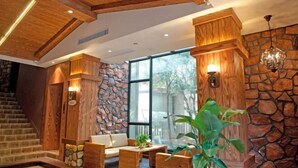 A modern interior with wooden beams, stone walls, and a staircase.