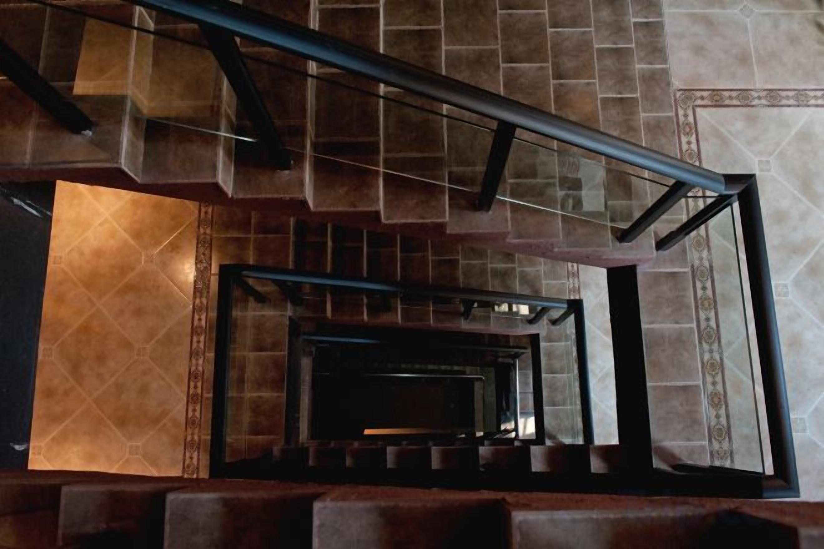 A staircase with a metal handrail and a view of a room with a fireplace.