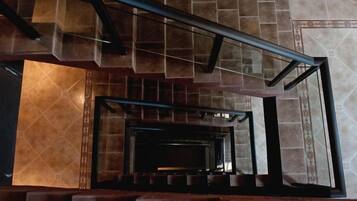 A staircase with a metal handrail and a view of a room with a fireplace.
