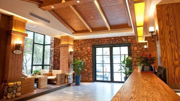 A lobby with a stone wall, wooden ceiling beams, and a reception desk.