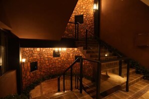 Una escalera con paredes de piedra y barandillas de metal, que conduce a un nivel superior.