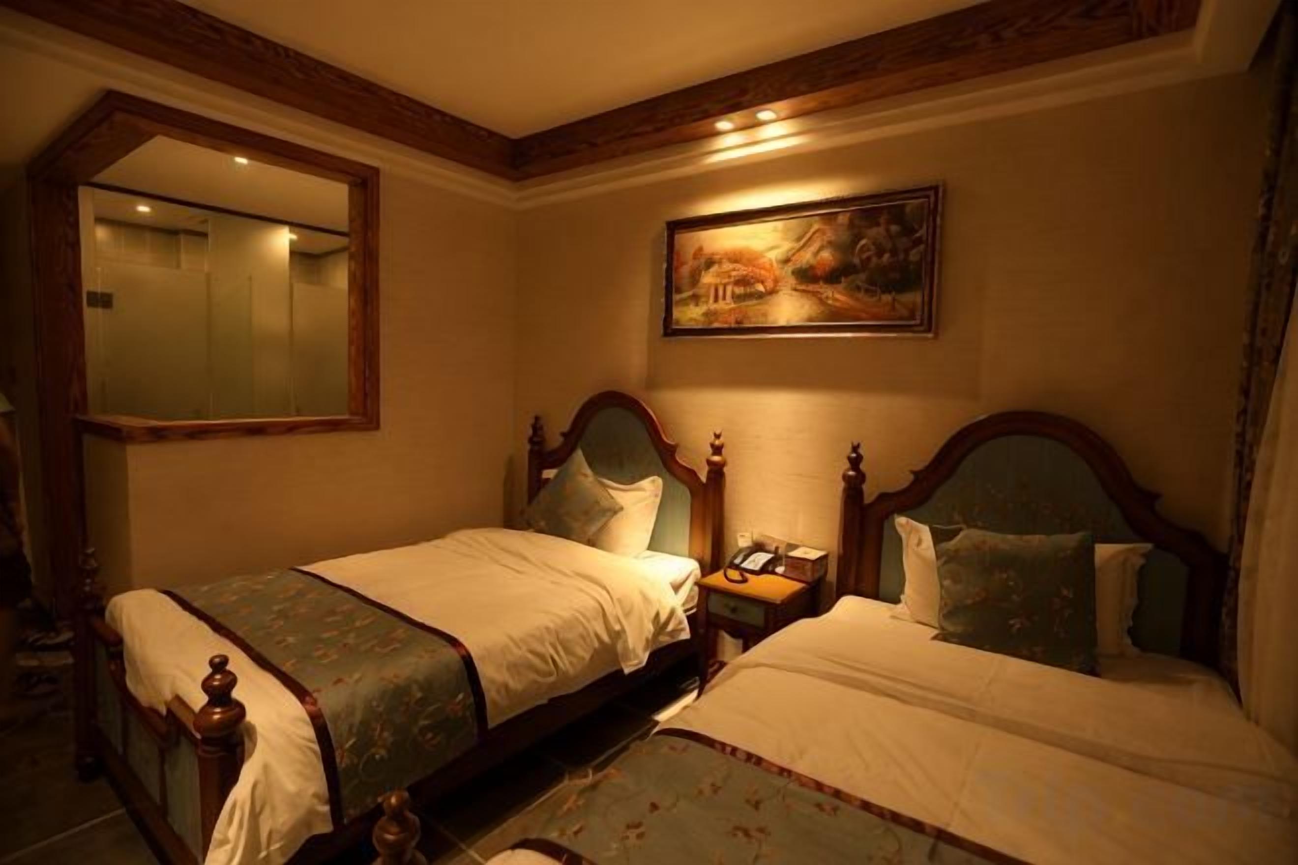 A hotel room with two beds, a large mirror, a painting on the wall, and a nightstand with a phone.