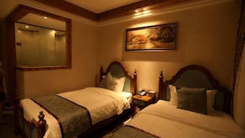 A hotel room with two beds, a large mirror, a painting on the wall, and a nightstand with a phone.