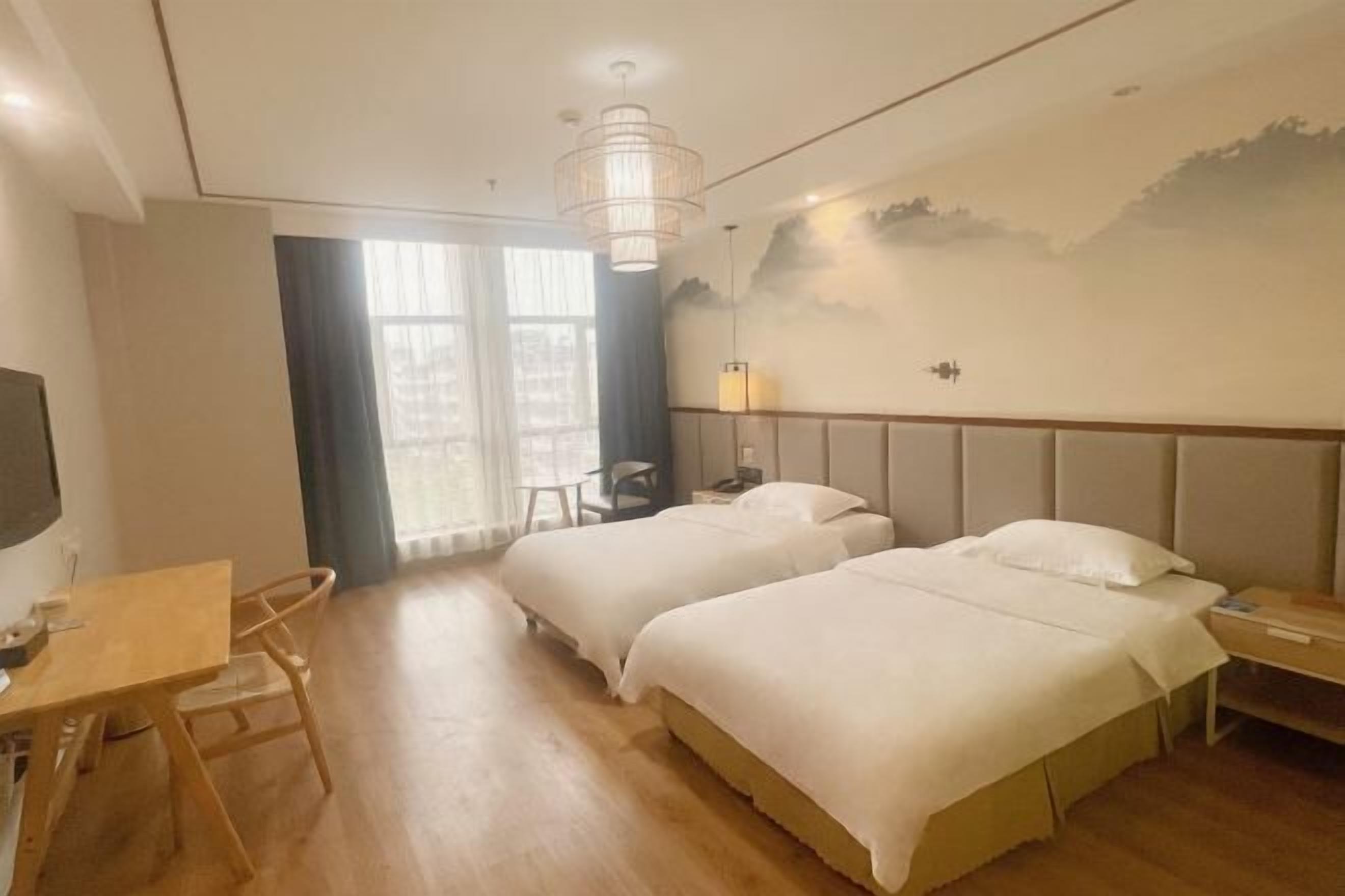 Une chambre d’hôtel avec deux lits, un bureau, une chaise, une télévision et une fresque murale.