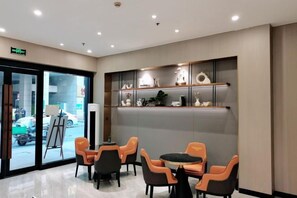 A hotel lobby with a reception desk, seating area with chairs, and decorative shelves. - Jingan Hotel (Shaoxing Keqiao Yintai Lantian Shixin Plaza) (Shaoxing)