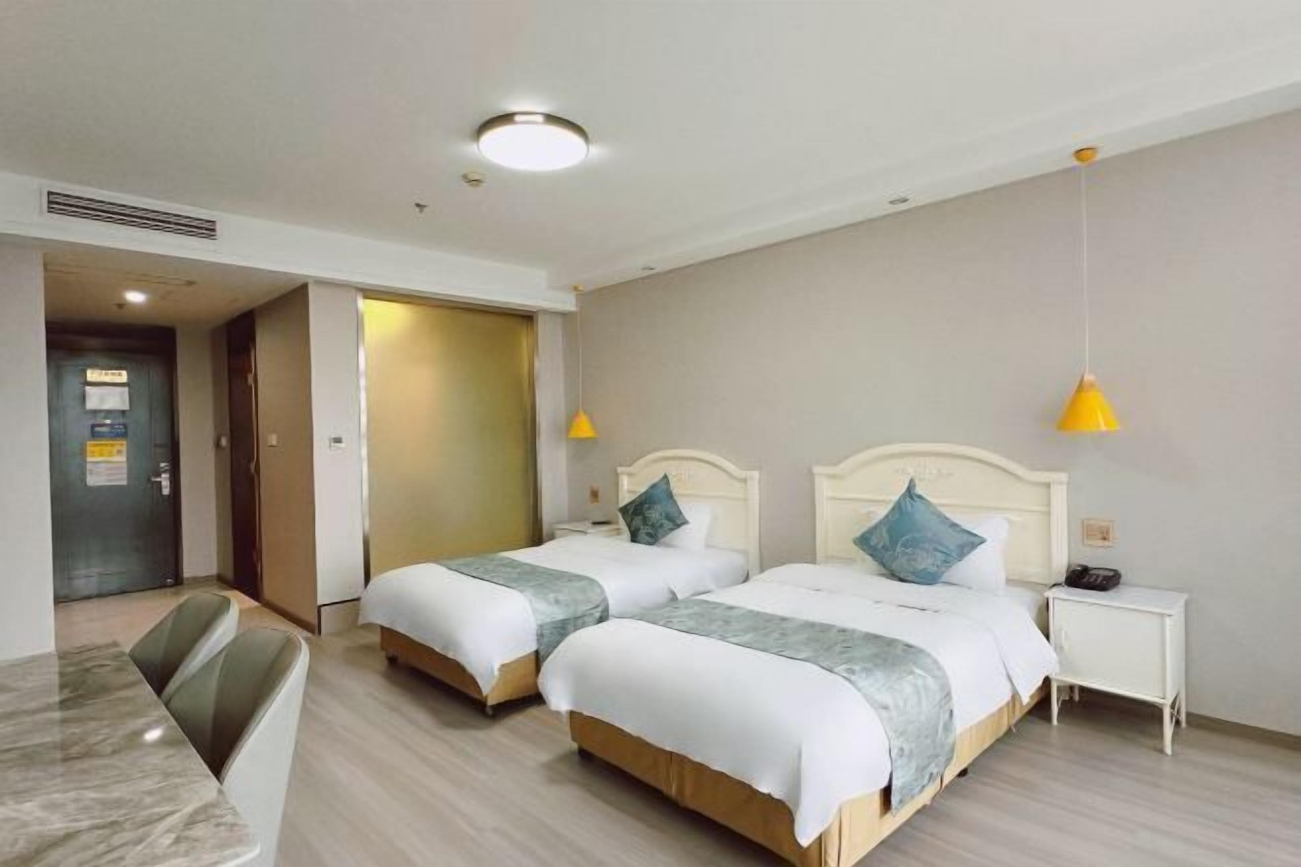 Ein Hotelzimmer mit zwei Betten, einem Schreibtisch und einem Stuhl.