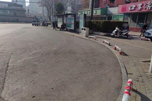 Escena callejera con una parada de autobús, un paso de peatones y un scooter estacionado.