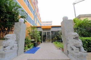 Entrada de un edificio con alfombra azul, estatuas de leones de piedra y puerta de vidrio.