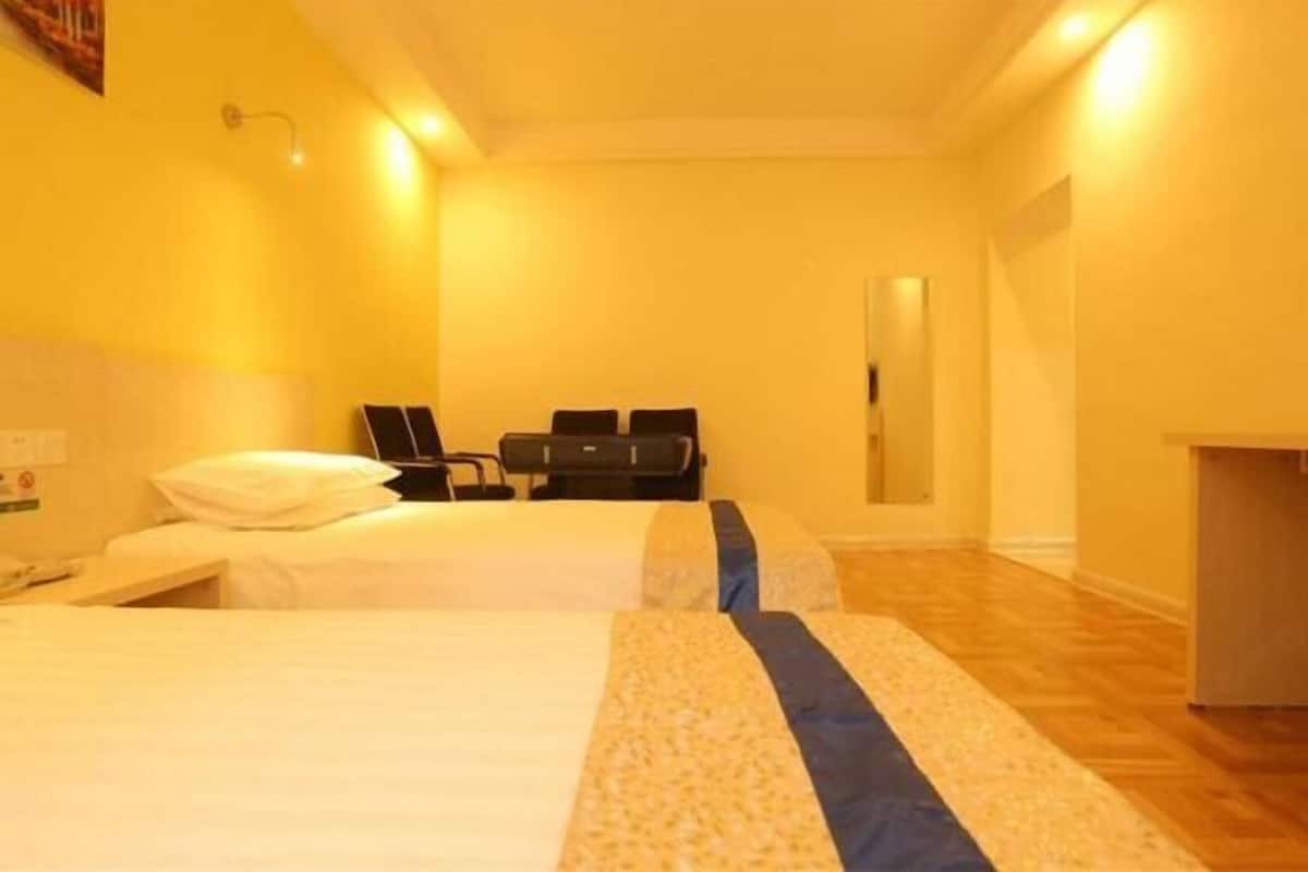 A hotel room with two beds, a desk, a chair, and a small table.