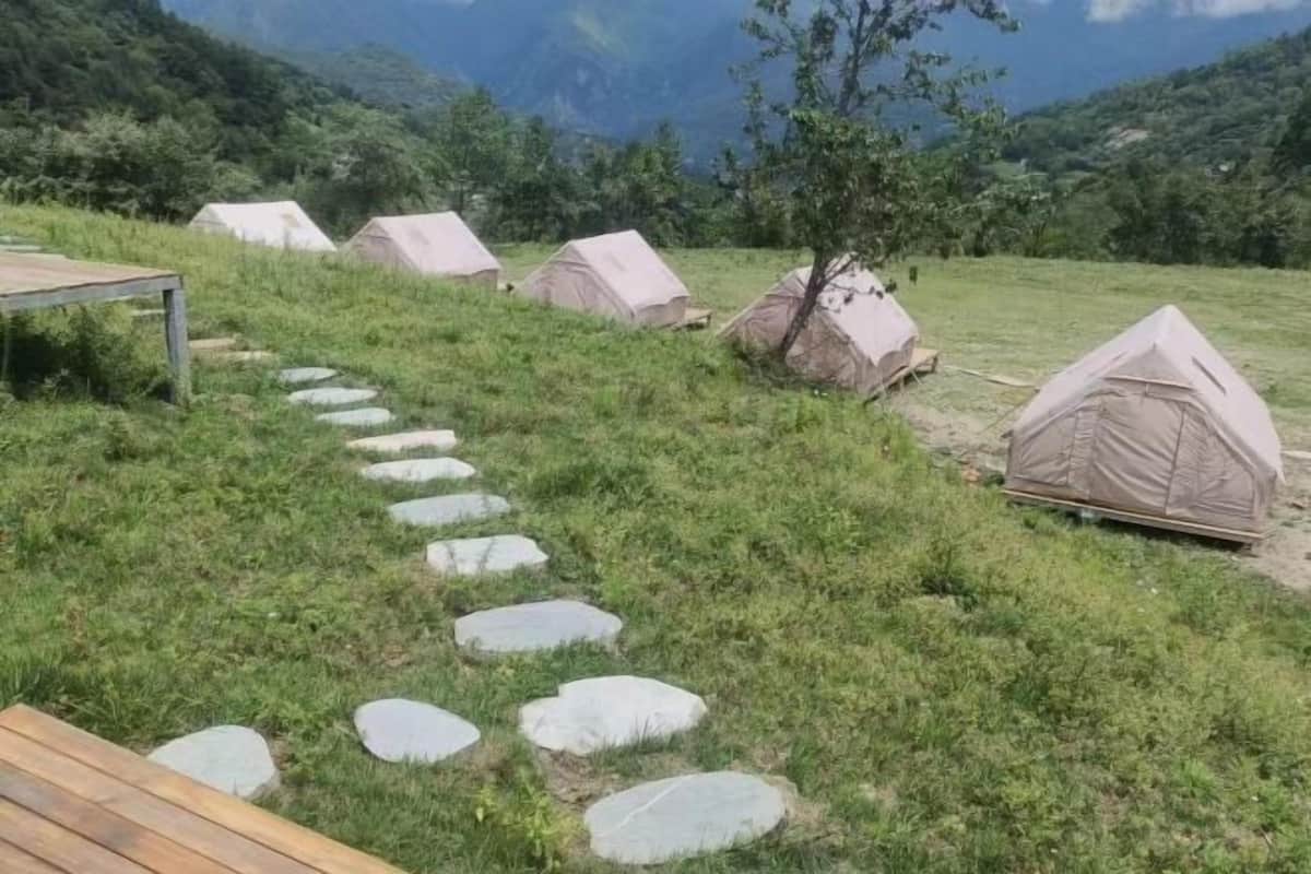 Un camping con tiendas de campaña, una terraza de madera y un sendero de piedra.