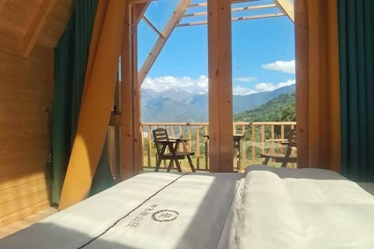 Una cabaña de madera con cama y vistas a las montañas.