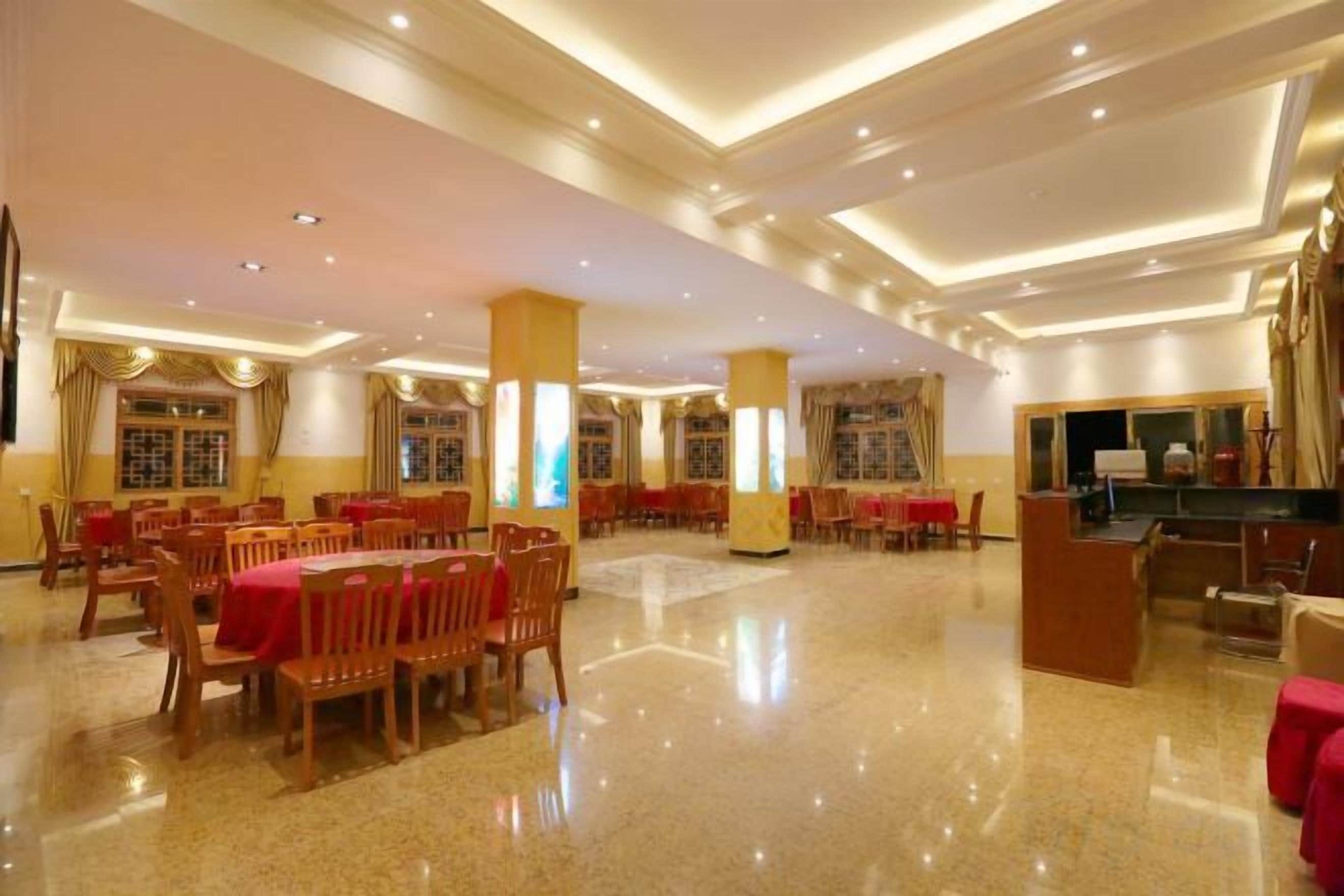 Un amplio vestíbulo de hotel con varias zonas de restauración, una recepción y una gran araña.