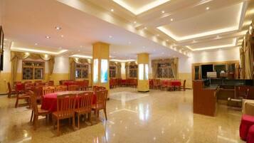 Un amplio vestíbulo de hotel con varias zonas de restauración, una recepción y una gran araña.