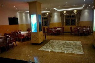 Un comedor amplio con varias mesas y sillas, un pilar central y un piso con diseño.