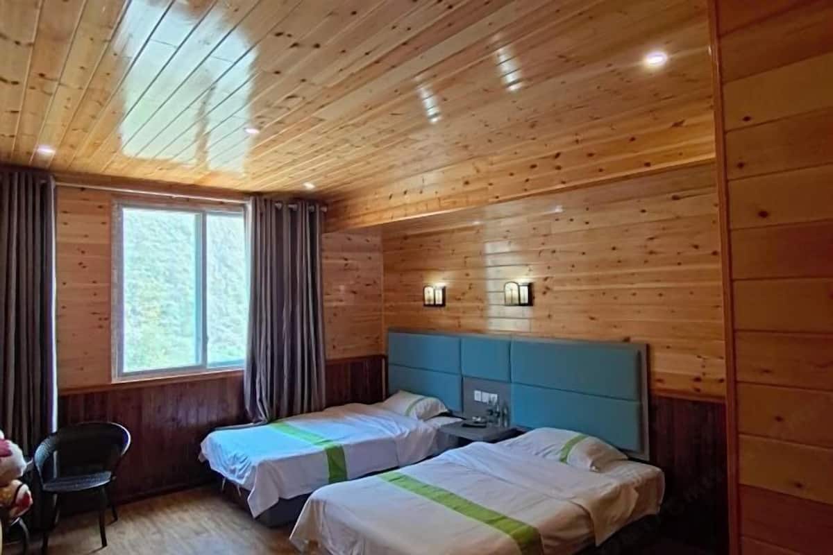 Una habitación con paneles de madera, dos camas, una silla y un ventanal.