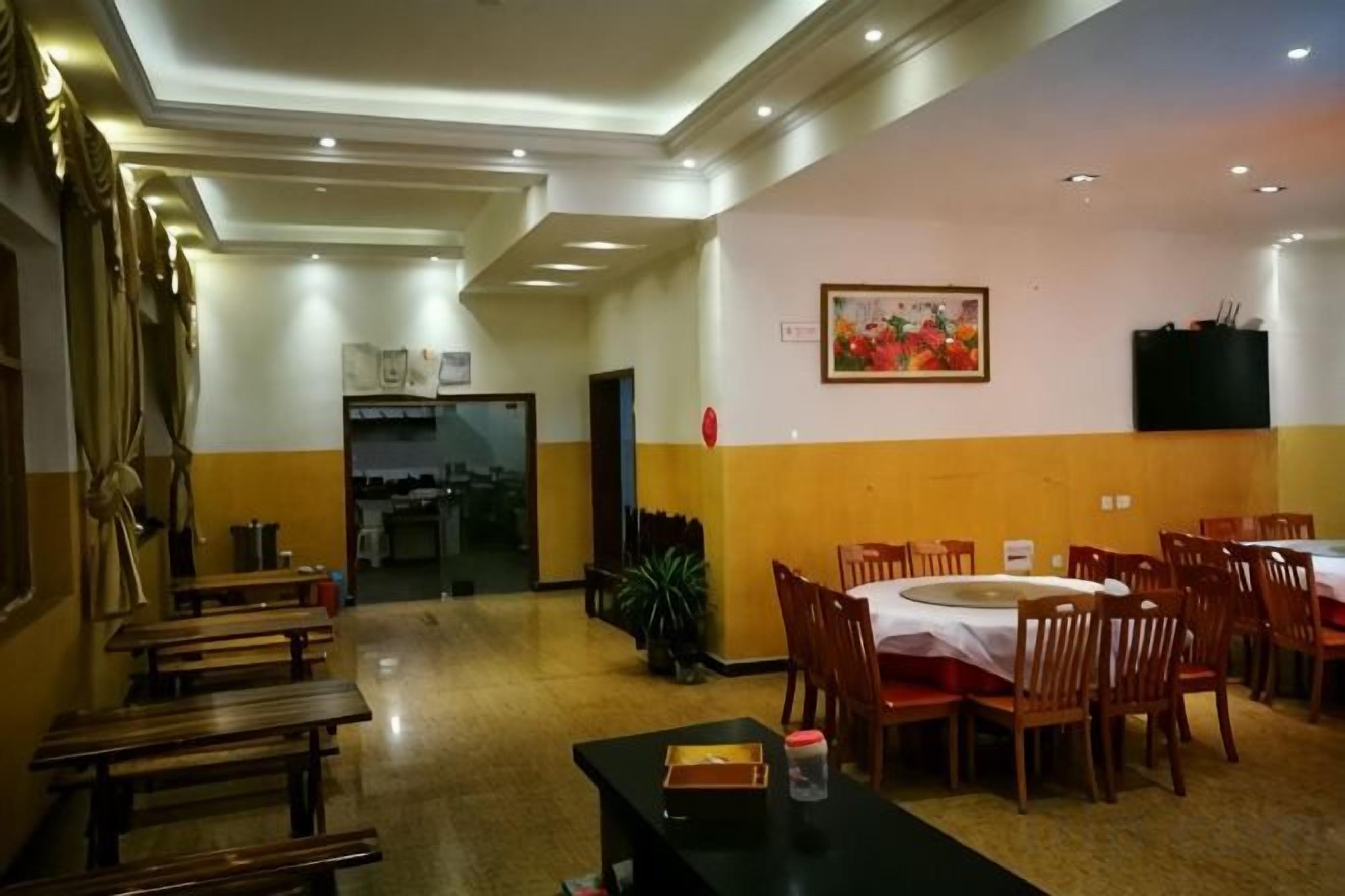A hotel dining area with tables and chairs, a long corridor with benches, and a door leading to another room.